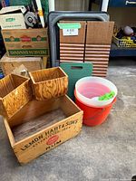 Overview of wood boxes, washboards, plastic buckets, and a green cutting board in a garage setting