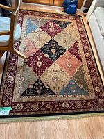 Top down view of Shaw Living oriental area rug showing patchwork pattern with dining chair and part of sofa visible.