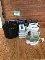 Photo shows black enamel canning pot with lid, white Cuisinart electric steamer, Salton appliance, ice cube trays, metal rack on wooden floor. Green tape marks chips on pot.