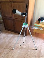 Side angle showing full telescope tube and tripod with adjustment handles on mounting arm.