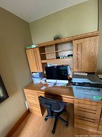 Full view of vintage Palliser oak office desk and hutch with black office chair in front. Desk has drawers and storage cabinets.