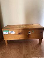 Photo showing front and side of vintage wood chest with stickers and painted flowers on lid.