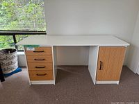 Front view of white office desk with four drawers on left and cabinet door on right.
