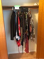 Full closet view of women's clothing items on hangers showing assorted jackets, dresses, tops in various prints and colors.