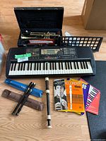 Full lot including Yamaha keyboard with sheet music stand, Jupiter trumpet in case, two recorders with cases, and four music books on floor.