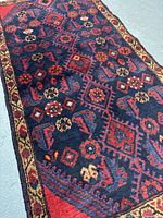 Full view of the rug showing intricate geometric and floral patterns in dark indigo, red, and yellow tones.
