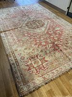 Overall view of rug on wood floor showing central design and discoloration