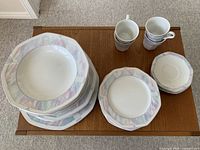 Set of Savoir Vivre china with pastel geometric borders, displaying multiple pieces including plates, bowls, cups, and saucers.
