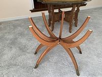 View of smaller brass table with curved wooden legs and brass capped feet, tray top detached and upside down on floor.