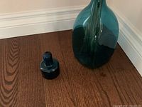 Photo showing the vase with the stopper placed adjacent on the floor, highlighting the deep blue color and smooth glass texture.