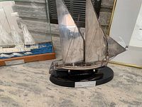 Two silver plated ship models side by side—’America Sailing Boat – Chicago’ front right, and another schooner in a wood/glass display case behind