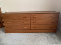 Front view of dresser showing six drawers and wood finish