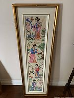 Vertical photo of framed Oriental-themed cross stitch needlework showing multiple traditionally dressed figures and nature motifs in a bamboo-style frame.