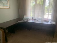 Large corner desk assembled from three sections in a corner by a window, showing overall size and condition.