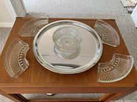 Glass serving dish set arranged on wooden table showing revolving silver-tone base and four glass bowls