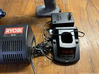 Close-up of one Ryobi 18V black battery charger with power cord on wooden surface.