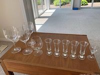 Photo showing all glasses on wooden surface, including 3 red wine glasses, 1 brandy glass, and 6 sherry glasses.