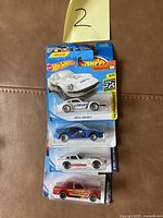Photo showing a set of four unopened Hot Wheels cars on a single card, with a note '2' above them.