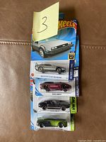 Four unopened Hot Wheels cars still in packaging, displaying various models including the Back to the Future Time Machine and Toyota 2000 GT