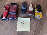 Five assorted toy vehicles displayed on wooden floor, showing variety in style and color.