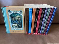 Side view of all 13 books in the A Series of Unfortunate Events, showing colorful spines and titles