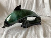 Photo showing side profile of Blue Mountain ceramic dolphin figurine with dark green and black glaze, glossy finish, leaping pose on wave base.
