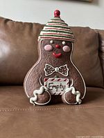 Front view of the full gingerbread man cookie jar with a hat lid in place, showing detailed facial features and decoration.