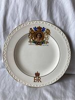 Front of the white porcelain commemorative plate decorated with crest, portrait, and gold royal cipher for Queen Elizabeth II 1953 coronation.