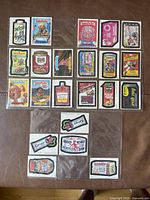 Top-down image of collection of vintage Whacky Packages and Garbage Pail Kids trading cards arranged in rows on a brown surface.