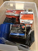 Plastic tub with various boxes of finish nails including Paslode, Craftsman, and Charm Air boxes.