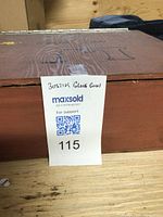 Wooden storage box with handwritten label 'Bostik Glue Gun' and auction tag number 115 attached to the box.