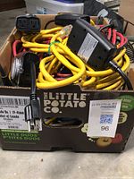 Box of assorted extension cords with yellow and black cables, multiple plugs visible.