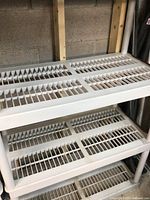 Close-up of two shelves showing open grid slatted design with vertical slats in grey resin/plastic material.