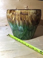 Front exterior view of large ceramic planter showing green to brown glaze and measuring tape for size reference.