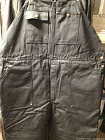 Front view of black insulated heavy canvas coveralls showing multiple pockets and snap closures.
