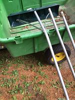 Side view of the black plastic blade with attached metal braces and part of the aluminum poles laying on ground.