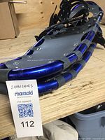 Close-up photo of Wind River logo on the black surface of the snowshoe showing blue aluminum frame edges.