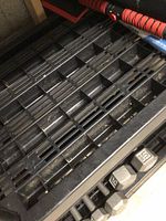 Top view of black plastic shelving slatted surface with elongated slots, showing dust and minor wear.