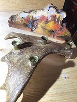 Photo showing the antler candle holder with four brass cups and the painted burl art piece behind it.