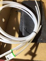 Coiled clear plastic tubing with a label attached, against a cardboard background.