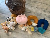 Overview of basket with 11 plush toys, 3 travel neck cushions and playing cards