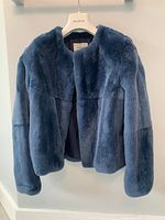 Front view of blue rabbit fur jacket on hanger