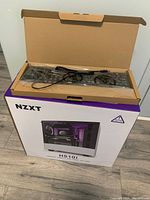 Opened box showing NZXT H510i PC case box with keyboard in plastic wrapping on top inside the box