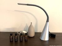 Desk lamp with flexible neck, silver and gray, shown with diffuser and essential oils on table.