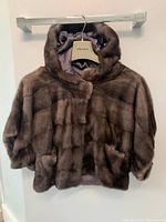 Front view of hooded fur jacket hanging on rack