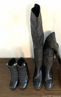 Photo showing two pairs of black women's boots, one thigh-high and one ankle high.