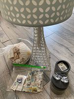 Close up of Eiffel Tower lamp base, bag of white sea shells, plastic bag with assorted stamps, and Swarovski swans in boxes on floor