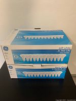 Two boxes of GE 65W indoor floodlight bulbs stacked, showing packaging and quantity details clearly.