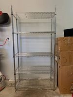 Full view of the chrome wire shelving unit showing five tiers with wire grid shelves and four upright poles.