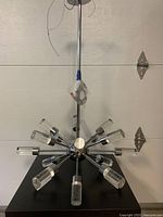 Side view of the modern ceiling light fixture showing the chrome sphere center, radiating arms, and acrylic cylinders.